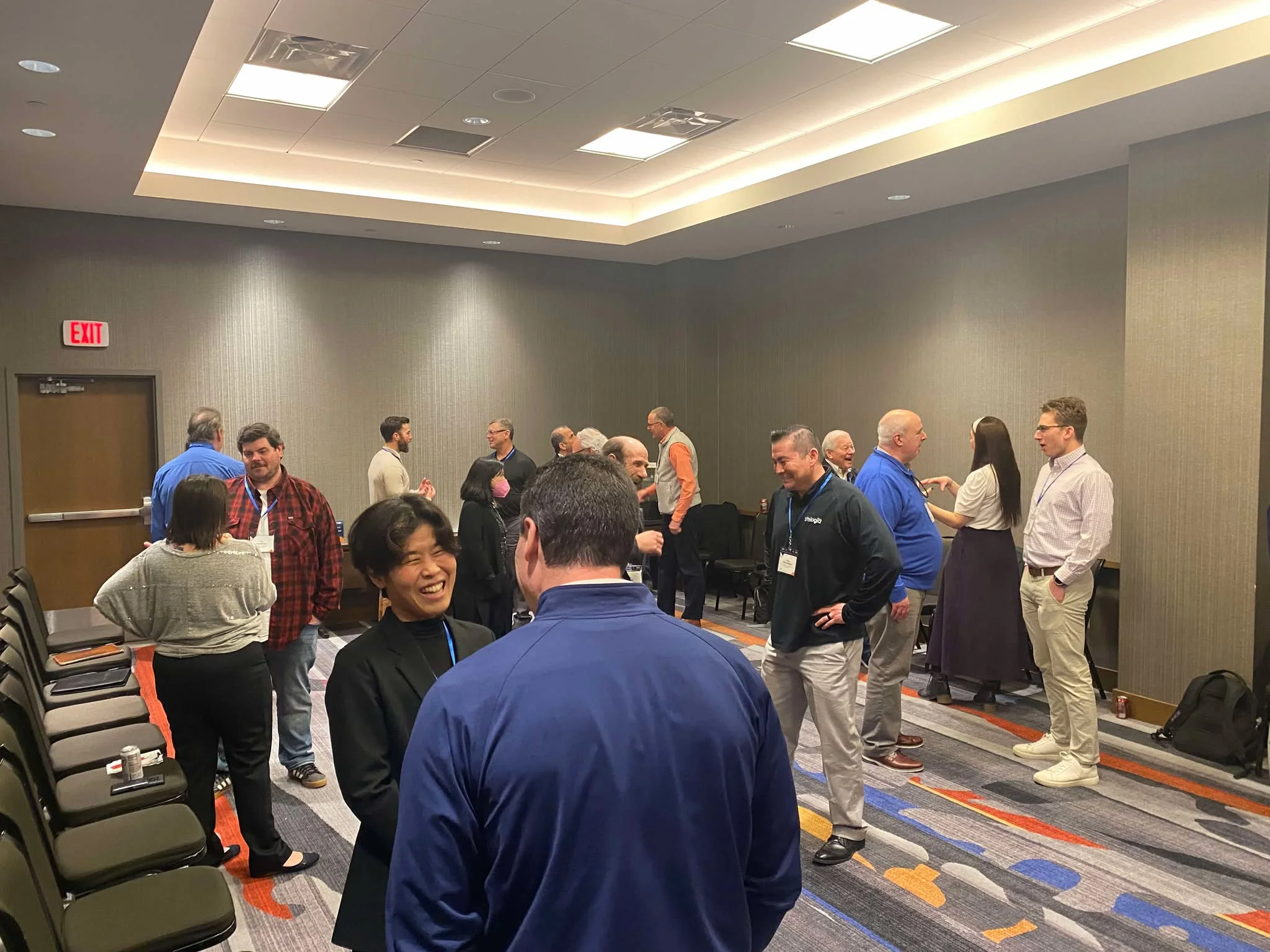 Professionals engaging in conversation and laughter during an applied improv workshop in a conference setting