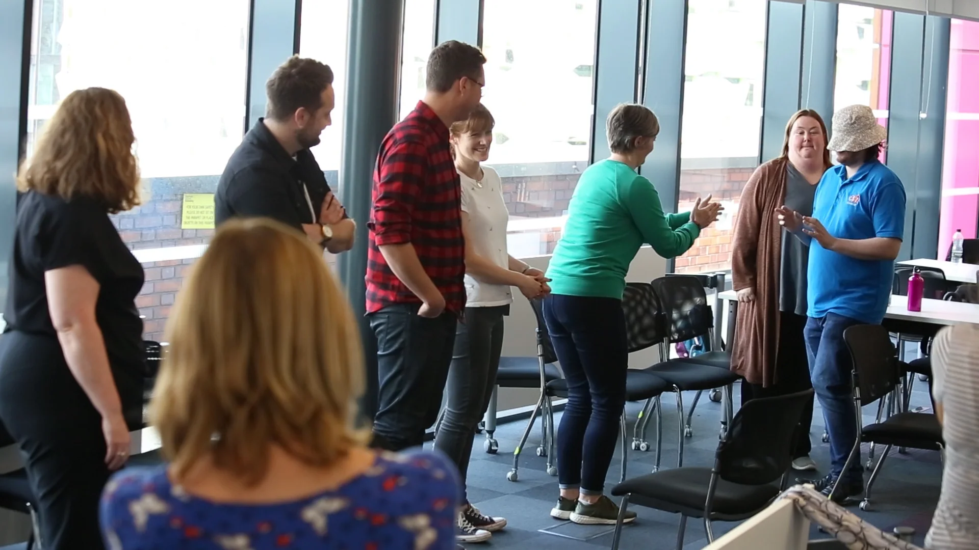 Facilitator guiding participants through an applied improv exercise in a bright modern space
